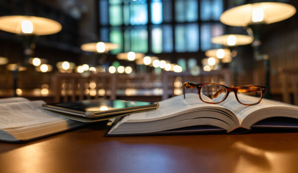 Digital Tablet and Eyeglasses On Books in Public Library